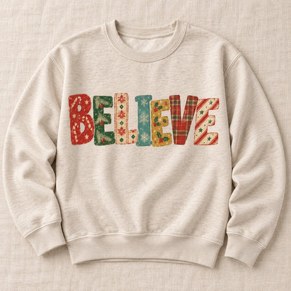Oatmeal crewneck sweatshirt laid flat with BELIEVE spelled in vintage holiday patterns of candy canes, plaid, snowflakes and holly