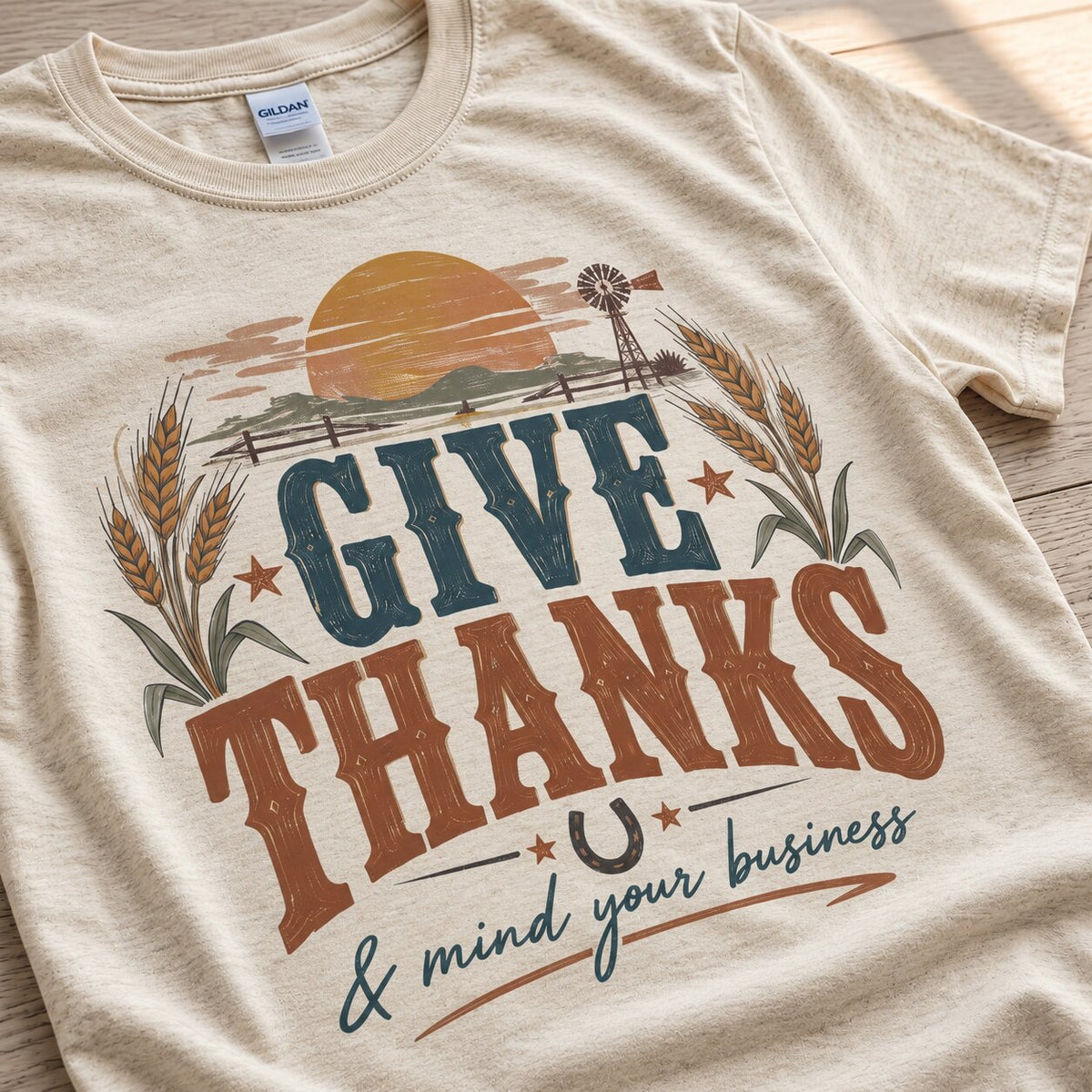 Close-up of the Give Thanks lettering in navy and rust with wheat stalks, a horseshoe and the script phrase and mind your business