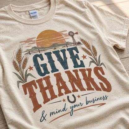 Close-up of the Give Thanks lettering in navy and rust with wheat stalks, a horseshoe and the script phrase and mind your business