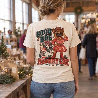 Woman wearing the Good Dog Naughty List tee, seen from behind, at a cozy holiday market