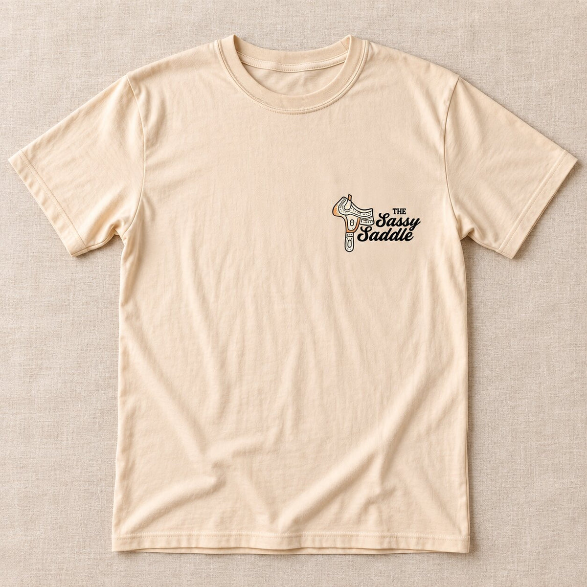 Front of the cream tee with a small Sassy Saddle logo on the left chest
