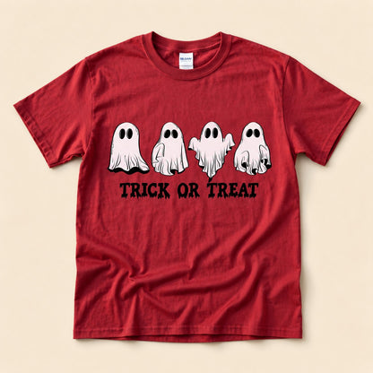 Red t-shirt flat lay on a cream background printed with four hand-drawn ghosts in different poses above dripping "TRICK OR TREAT" lettering.