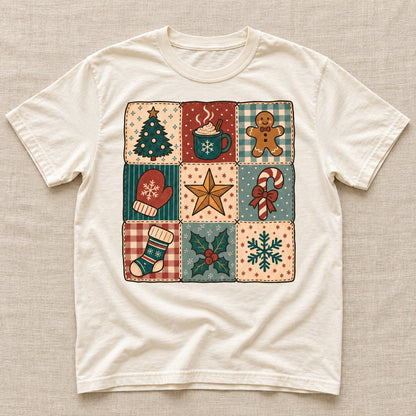 Cream tee laid flat with a Christmas patchwork graphic of a tree, cocoa mug, gingerbread, mitten, star, candy cane, stocking, holly and snowflake